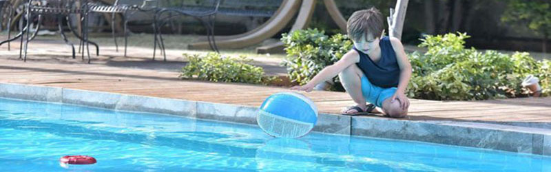 boy getting ball from side of pool